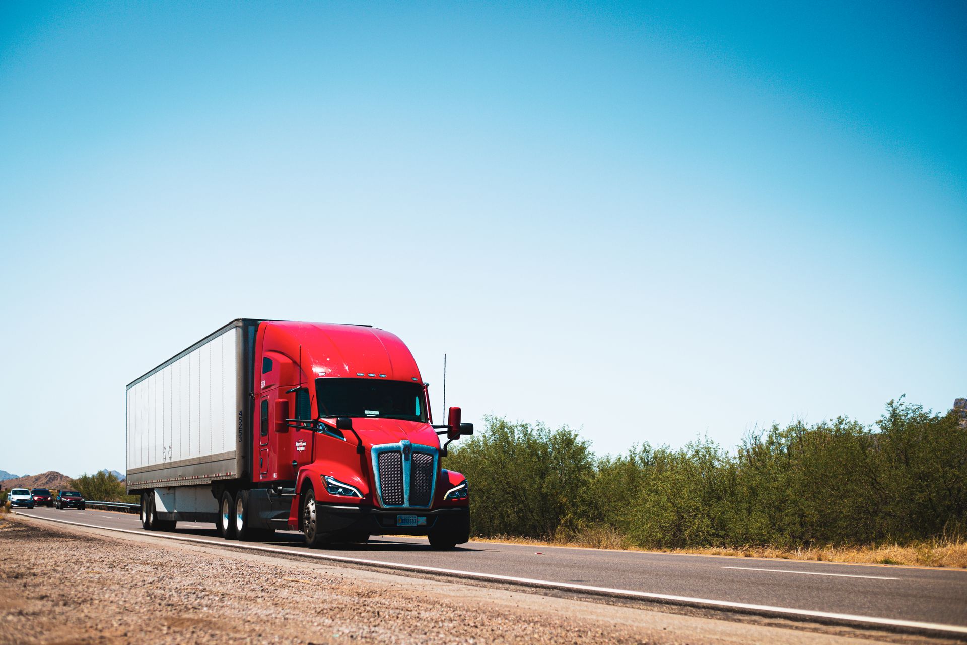 A red Kenworth semi truck traveling on an open highway
