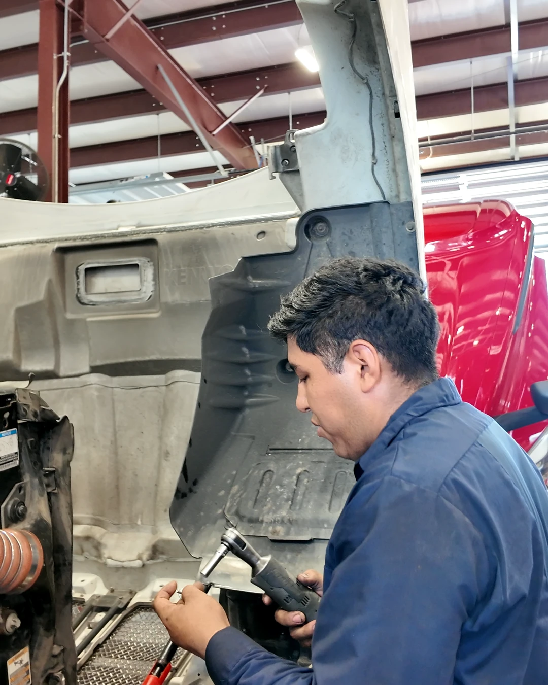 Mechanic working under an open truck hood at Trucker Heaven