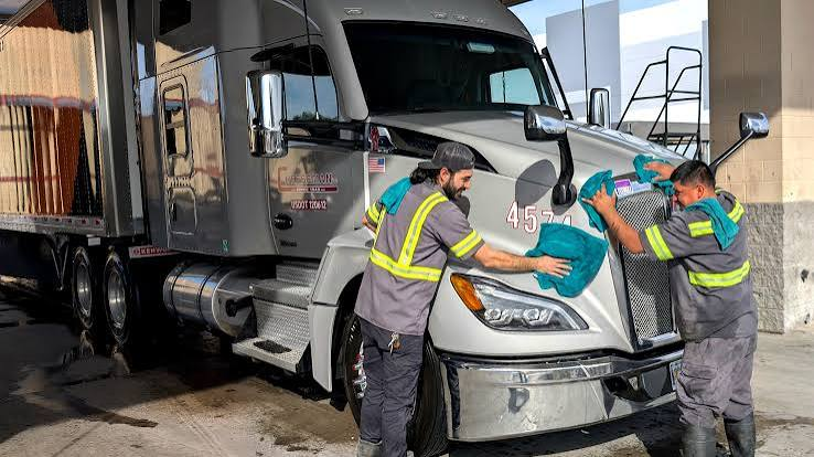 Workers washing a truck at a wash bay